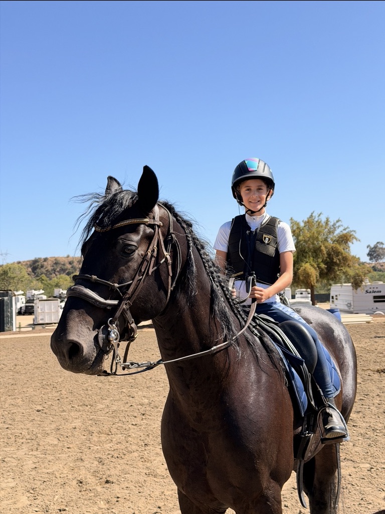 A smiling young rider on a black horse at Hansen Dam Horse Park